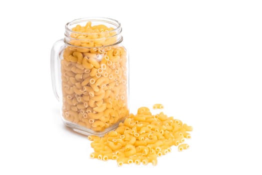 Uncooked Chifferi Rigati Pasta in Glass Jar Isolated on White Background. Fat and Unhealthy Food. Scattered Classic Dry Macaroni. Italian Culture and Cuisine. Raw Pasta