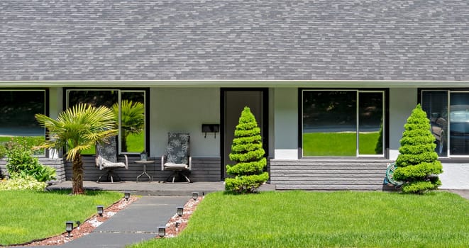 Main entrance of residential house with concrete pathway over the front yard on bright sunny day