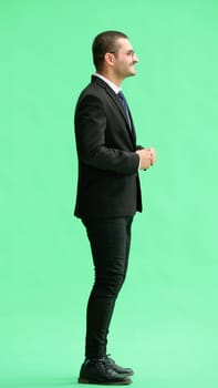 young man in full growth. isolated on green background profile.