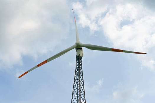 Wind turbine for generating electricity outdoors against the background of the sky and clouds. Concept of alternative energy sources