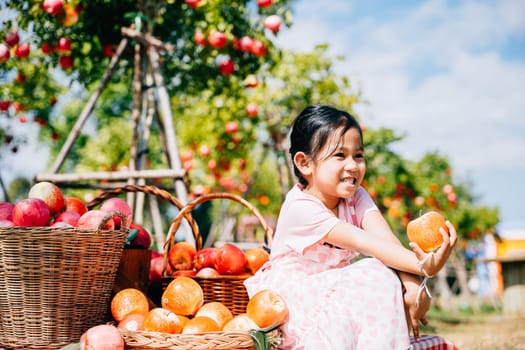 Amidst the orchard a happy girl holds a ripe apple. Kids gather fruits in baskets on the sunny farm a cheerful portrait portraying the joy of apple picking and nature's freshness.