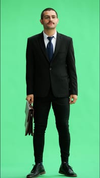 full-length portrait of a young man. standing isolated on green background.