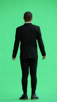 young man in full growth. isolated on green background. view from the back.