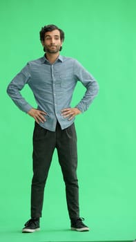 full-length portrait of a young man. standing isolated on green background.