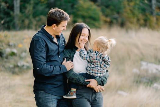 Dad hugging mom from behind with a little girl in her arms. High quality photo