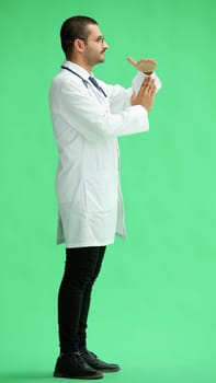 male doctor in a white coat on a green background shows a sign take a break.