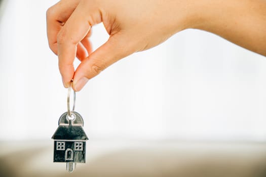 Hand holds house key marking homeowners' achievement. Agent presents model home symbolizing real estate success. Confidence and happiness shine.