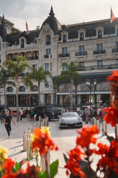 Monaco, Monte-Carlo, 22 October 2022: Square Casino Monte-Carlo at sunset, luxury cars, famous Hotel de Paris, wealth life, tourists take pictures of the landmark, pine trees, flowers. High quality photo