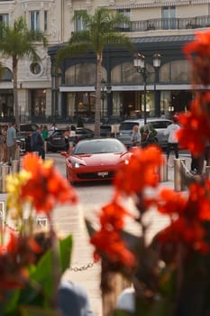 Monaco, Monte-Carlo, 22 October 2022: Square Casino Monte-Carlo at sunset, luxury cars, famous Hotel de Paris, wealth life, tourists take pictures of the landmark, pine trees, flowers. High quality photo