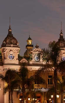 Monaco, Monte-Carlo, 12 November 2022: The famous square of Casino Monte-Carlo is at dusk, attraction night illumination, luxury cars, players, tourists, splashes of fountain. High quality photo