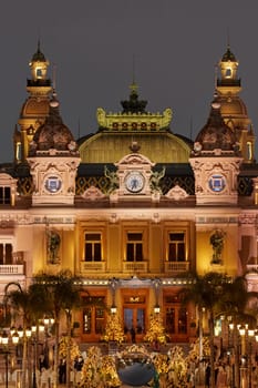 Monaco, Monte-Carlo, 12 November 2022: The famous square of Casino Monte-Carlo is at dusk, attraction night illumination, luxury cars, players, tourists, splashes of fountain. High quality photo