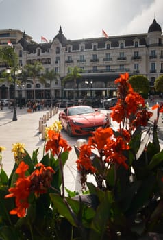 Monaco, Monte-Carlo, 22 October 2022: Square Casino Monte-Carlo at sunset, luxury cars, famous Hotel de Paris, wealth life, tourists take pictures of the landmark, pine trees, flowers. High quality photo