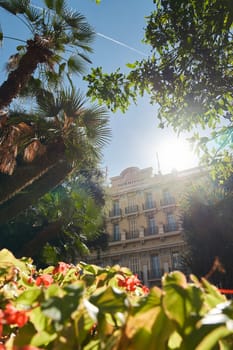 Monaco, Monte-Carlo, 09 November 2022: The Hotel Hermitage through flowers at sunny day, luxury life, building exterior of famous hotel, palm trees, sunshine, balcony. High quality photo