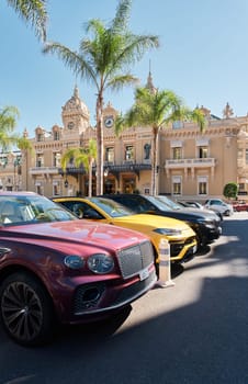 Monaco, Monte-Carlo, 21 October 2022: Square Casino Monte-Carlo at sunny day, a lot of luxury cars, Hotel de Paris, wealth life, tourists take pictures of the landmark, pine trees, blue sky, flowers. High quality 4k footage