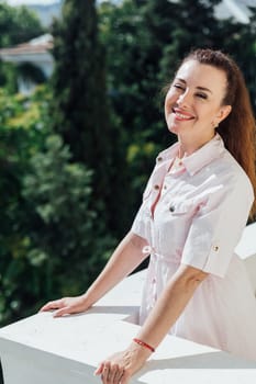 woman in summer light dress on balcony looking at the street