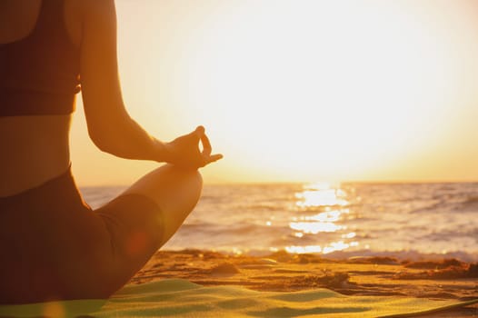 Close up of woman's hand practicing yoga, meditation in lotus position on the beach, feeling so comfortable and relaxing on vacation with golden light, healthy concept.