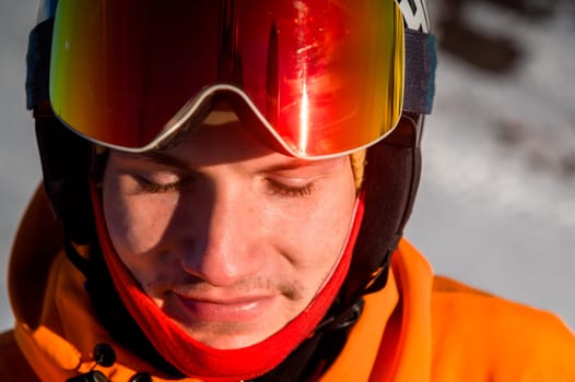 A cheerful skier with his eyes closed, stands and smiles. Happy man enjoying holiday in winter season