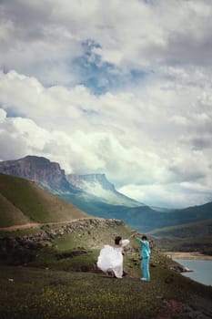 beautiful wedding couple in the mountains. gorgeous bride and groom holding hands and dancing in the mountains with clouds, a moment of true happiness.