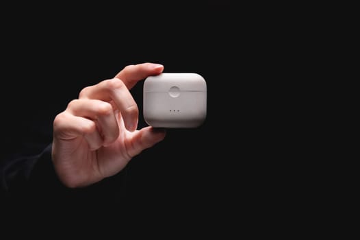 White wireless headphones. in the woman's hand there is a charger box for vacuum headphones, a white storage case.