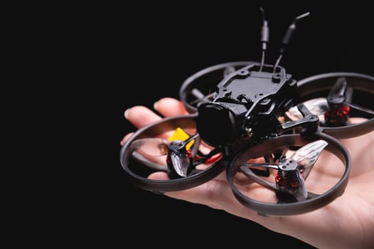 Hands holding a racing drone with a camera. Woman holding a radio-controlled mini quadcopter.