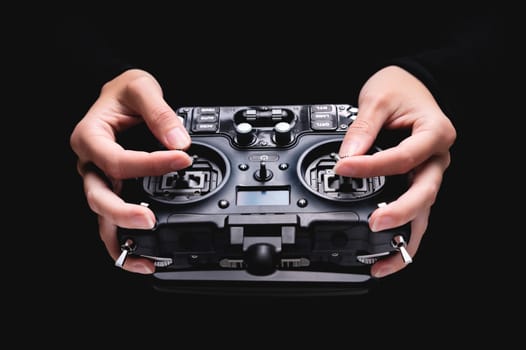 Remote control of FPV racing drone on black background in female hands, close-up.