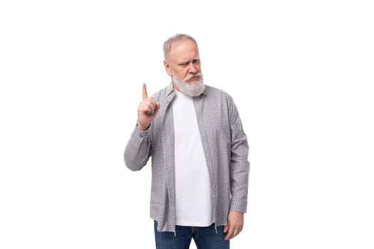 handsome gray-haired elderly man in a shirt shows his index finger up on a white background with copy space.