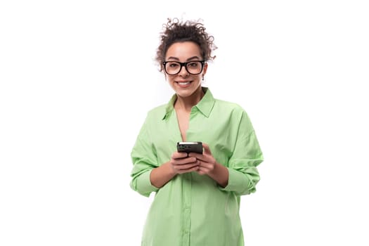 charming young slender female model dressed in a light green shirt chatting in a mobile phone on a white background. people lightstyle concept.