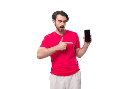 young handsome man with black hair dressed in a red t-shirt holds the phone screen forward.