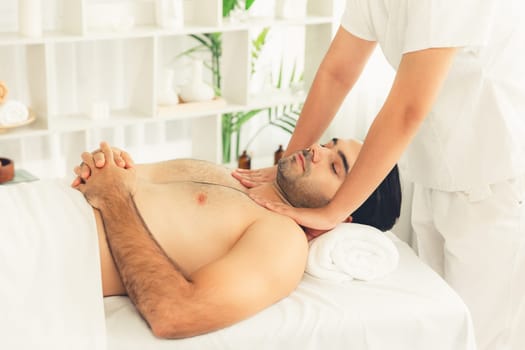 Caucasian man enjoying relaxing anti-stress head massage and pampering facial beauty skin recreation leisure in dayspa modern light ambient at luxury resort or hotel spa salon. Quiescent