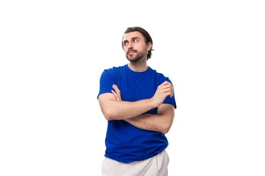 young smart brunette man with a beard dressed in a blue t-shirt is brainstorming on a white background.