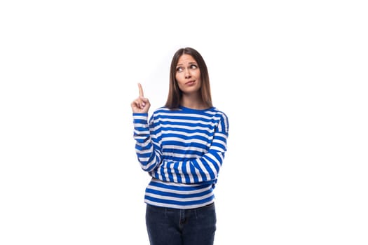 young european model woman wears a sweater with a sailor striped pattern points her hand to the side on a white background with copy space.