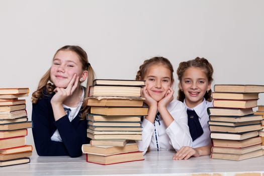 two schoolgirl girls with books in the library in class at the desk