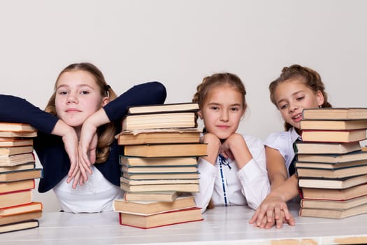 two schoolgirl girls with books in the library in class at the desk