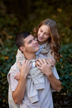 Young Cute Female Hugs Boyfriend. In Autumn Outdoor. Lovers Walking in Park. Attractive Funny Couple. Lovestory in Forest. Man and Woman. Cute Lovers in the Park. Family Concept. Happy Couple.