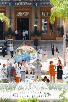 Monaco, Monte-Carlo, 21 October 2022 - Square Casino Monte-Carlo at sunny day, wealth life, tourists take pictures of the landmark, pine trees, blue sky. High quality photo