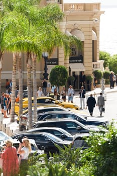 Monaco, Monte-Carlo, 21 October 2022 - Square Casino Monte-Carlo at sunny day, wealth life, tourists take pictures of the landmark, pine trees, blue sky. High quality photo