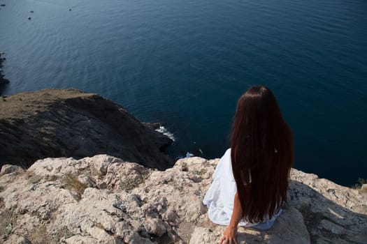 woman with long hair in dress on cliff cliff by the sea