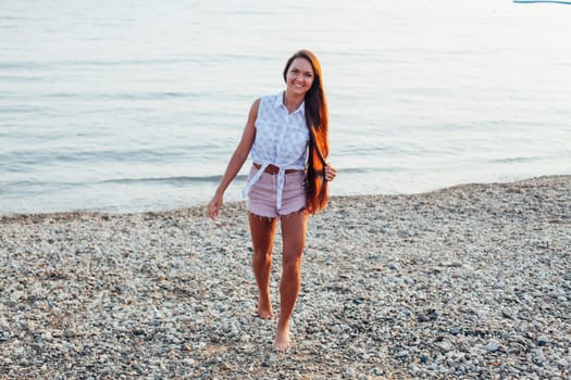 woman with long hair walks on the sea beach at dawn