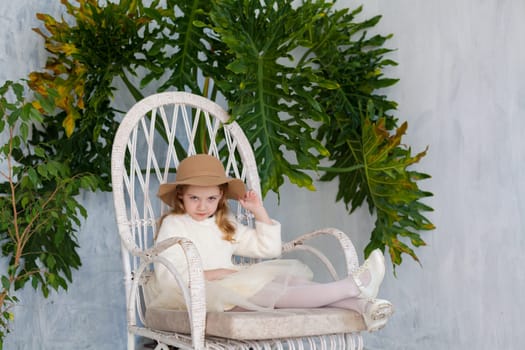 fashionable girl in a hat with fields sitting in a white chair