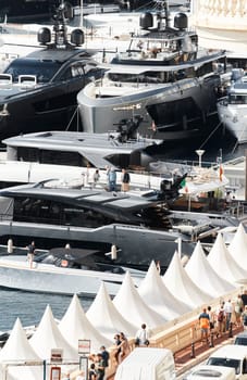 Monaco, Monte Carlo, 27 September 2022 - Invited wealthy clients inspect megayachts at the largest fair exhibition in the world yacht show MYS, port Hercules, yacht brokers, sunny weather. High quality photo