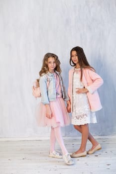 Two beautiful fashionable girl girlfriends in white pink poatya