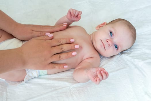 Women's hands stroke the baby's tummy. Mother care concept.