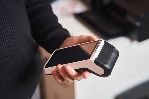 Bank terminal for contactless payment. Acquiring. Young man holds a terminal in his hands.