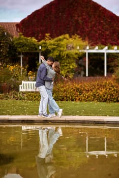 lovely young couple kissing outdoors in autumn. Loving couple walking in nature. Autumn mood. Happy man and woman hugging and kissing in autumn. Love. Fashionable couple outdoors. Fashion, people and lifestyle. Stylish couple in autumn outfit.