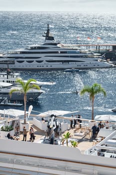 Monaco, Monte Carlo, 27 September 2022 - Rich clients visitors examine a helicopter standing on the deck of a yacht club, the largest fair yacht show, port Hercules, yacht brokers, sunny weather. High quality photo