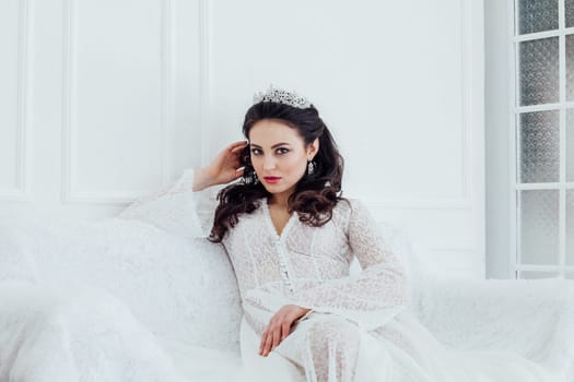 bride in wedding dress sitting on a white couch