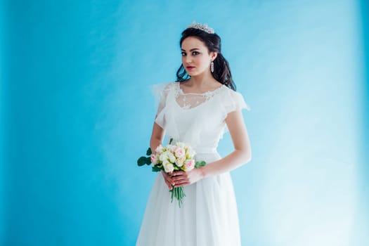 Princess Bride in a white dress with a Crown on a blue background flower in hands