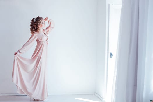 girl bride in pink Pajamas posing in a white room