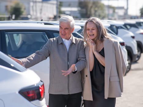 An elderly Caucasian man gives a new car to his beloved woman