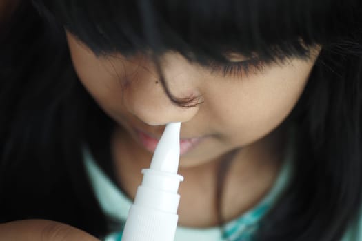 close up of sick child using nasal medicine spray.